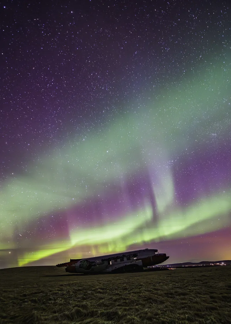 Purple and green curtains of aurora overhead