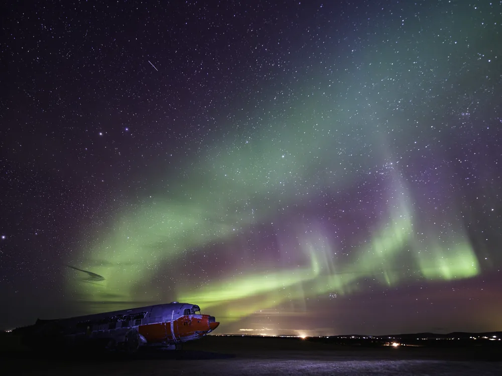 The DC-3 at night beneath green northern lights