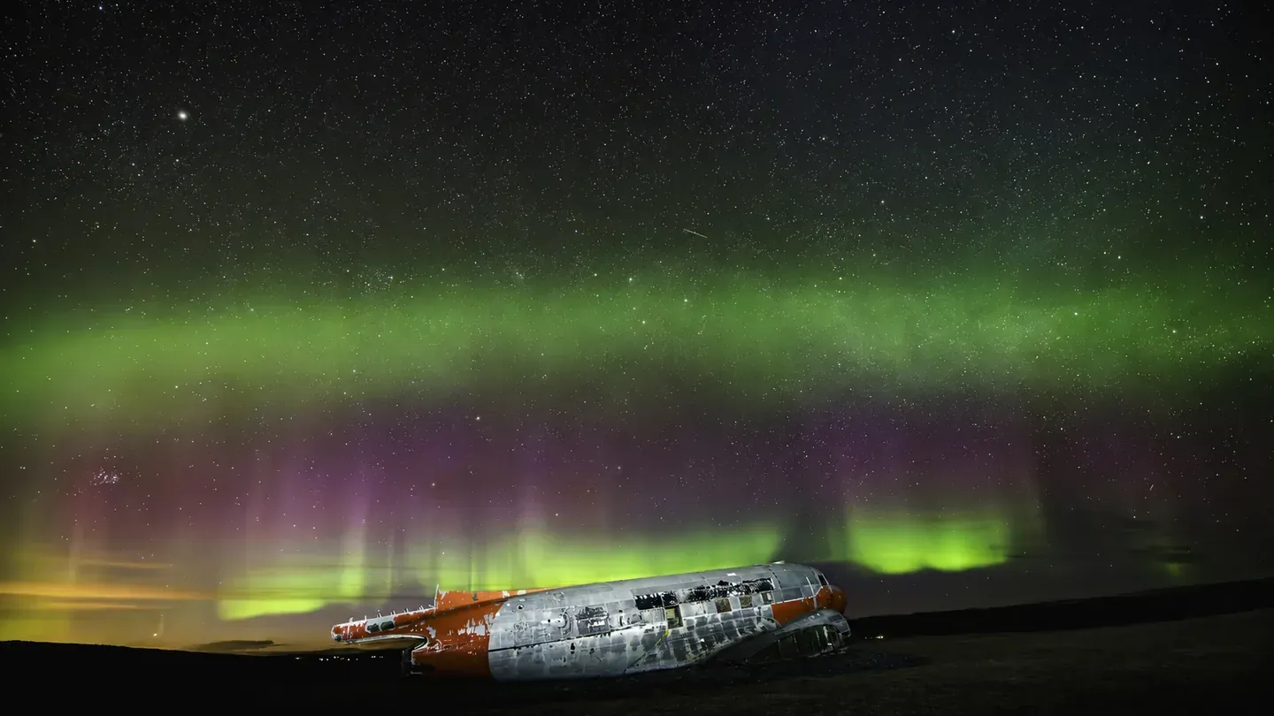 Green and purple northern lights above the DC-3 at Eyvindarholt